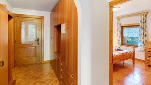 Un pasillo con puertas de madera, una cama con cortinas florales y una ventana con vistas.
