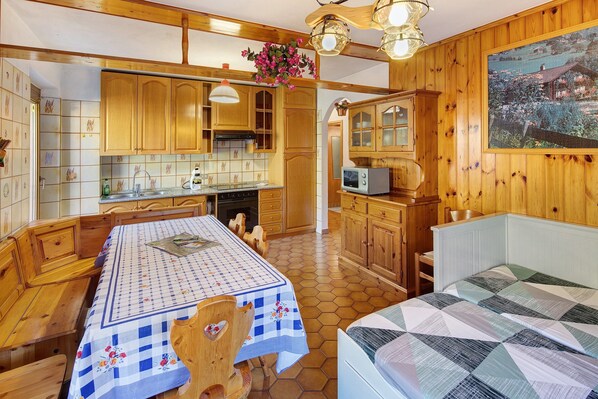 A cozy kitchen with wooden cabinets, a dining table with a checkered tablecloth, and a painting on the wall.