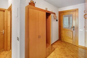 A hallway with wooden doors, a wardrobe, and a tiled floor.