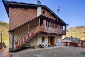 A two-story wooden building with a balcony, a staircase, and a view of the surrounding landscape.