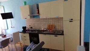 Ett kompakt kök med en matplats, en platt-TV och en soffa.