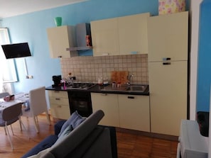 Eine kompakte Küche mit Essbereich, einem Flachbildfernseher und einer Couch.