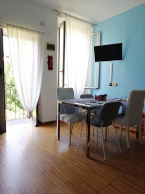 A dining area with a table, chairs, and a television mounted on the wall. - Locami Apartment Ca' Granda (Milan)