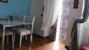 Ett rum med ett matbord, stolar, en krukväxt och en gardin.