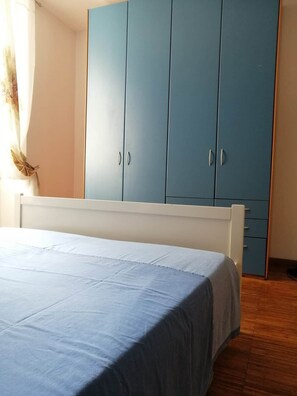 Ein Schlafzimmer mit einem Bett, einem Kleiderschrank und einem Fenster mit Vorhängen.