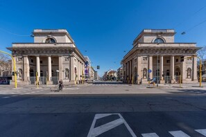 Straßenkreuzung mit klassischer Architektur, Ampeln und einer Fußgängerüberweg.