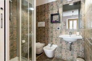 Ein Badezimmer mit Dusche, Toilette, Bidet und Waschbecken.