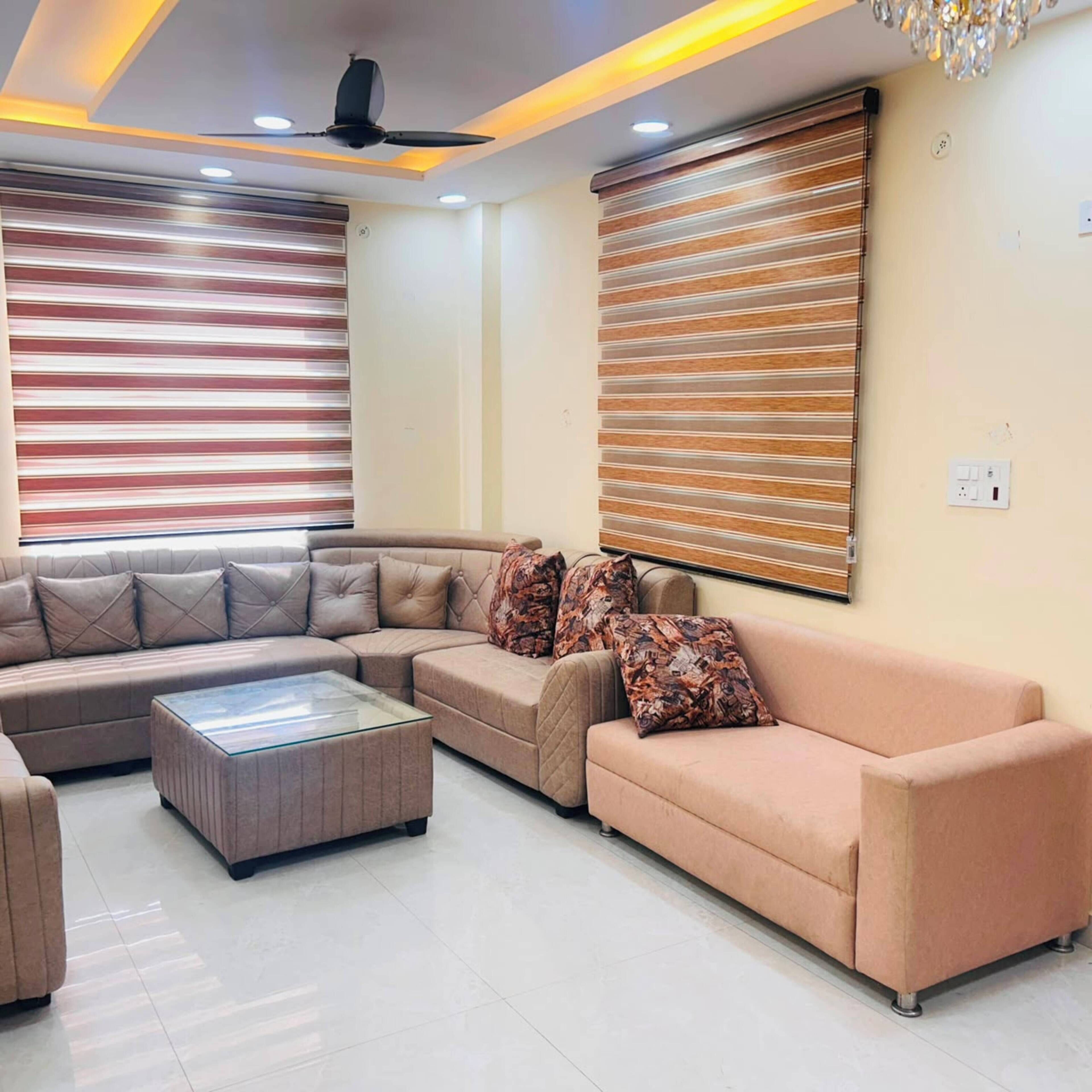 A modern living room with a sectional sofa, a glass coffee table, and a decorative chandelier.