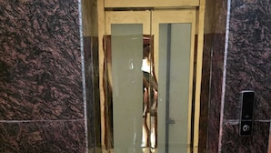 An elevator with a glass door, a metal handle, and a control panel on the wall.