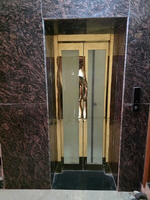 An elevator with a glass door, a metal handle, and a control panel on the wall.