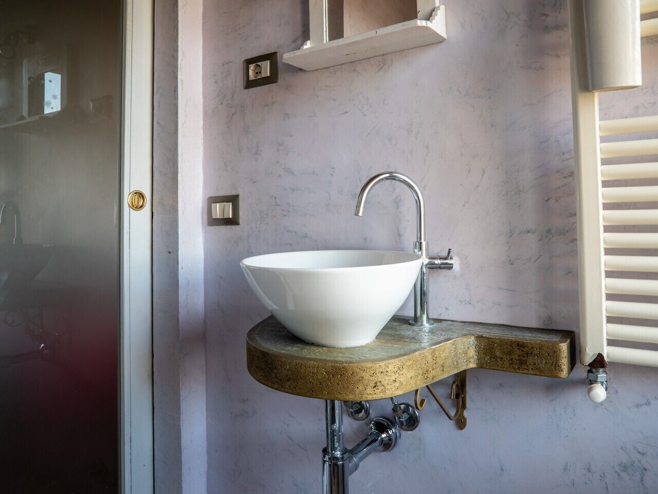 Ein Badezimmer mit einem weißen Waschbecken auf einer gewölbten Arbeitsplatte, einem Chromarmaturen und einem Handtuchhalter.