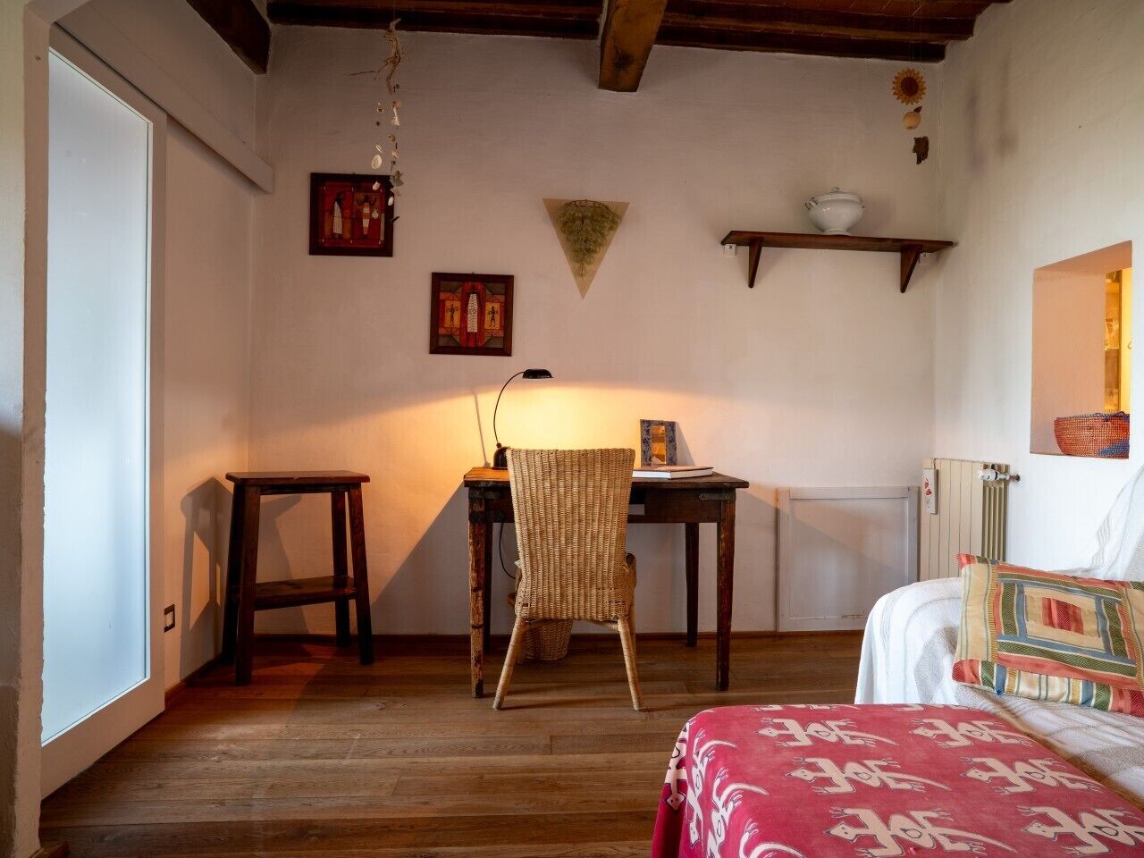 A room with a bed, a chair, a table, and a radiator.