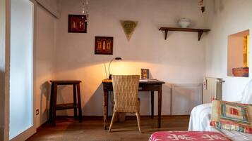 A room with a bed, a chair, a table, and a radiator.