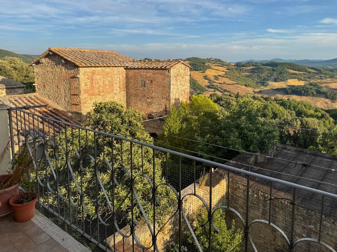 Ein Balkon mit Blick auf ein Steinhaus und die umliegende Landschaft.