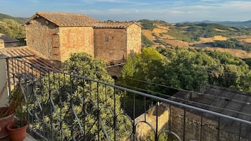 Ein Balkon mit Blick auf ein Steinhaus und die umliegende Landschaft.