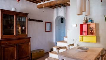 A dining area with a wooden table and chairs, a cabinet, and a staircase with a blue door.