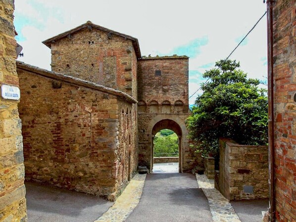 A narrow alleyway with a stone archway leading to a building with a brick facade.