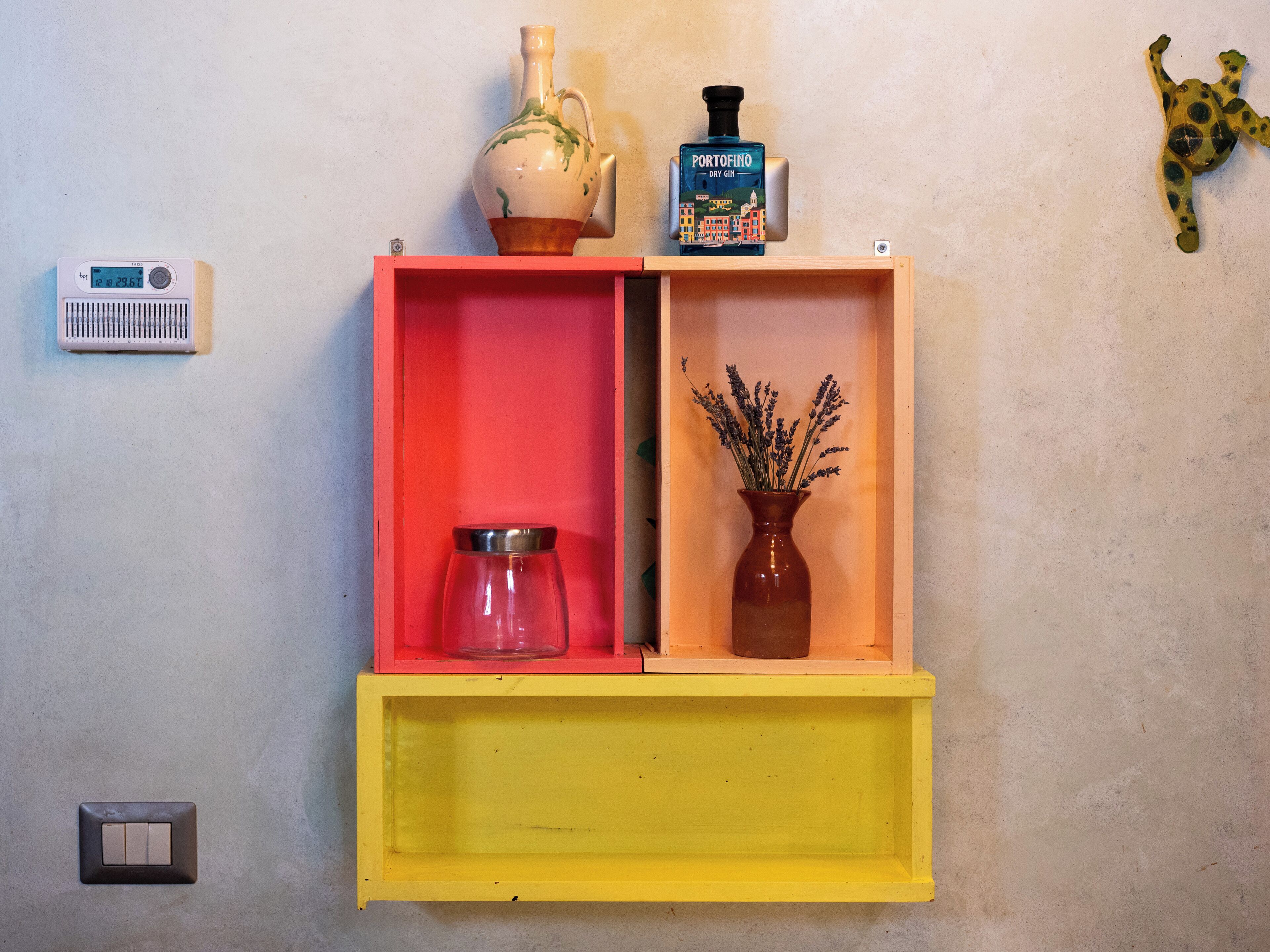 A shelf with a vase, a bottle, and a radio.