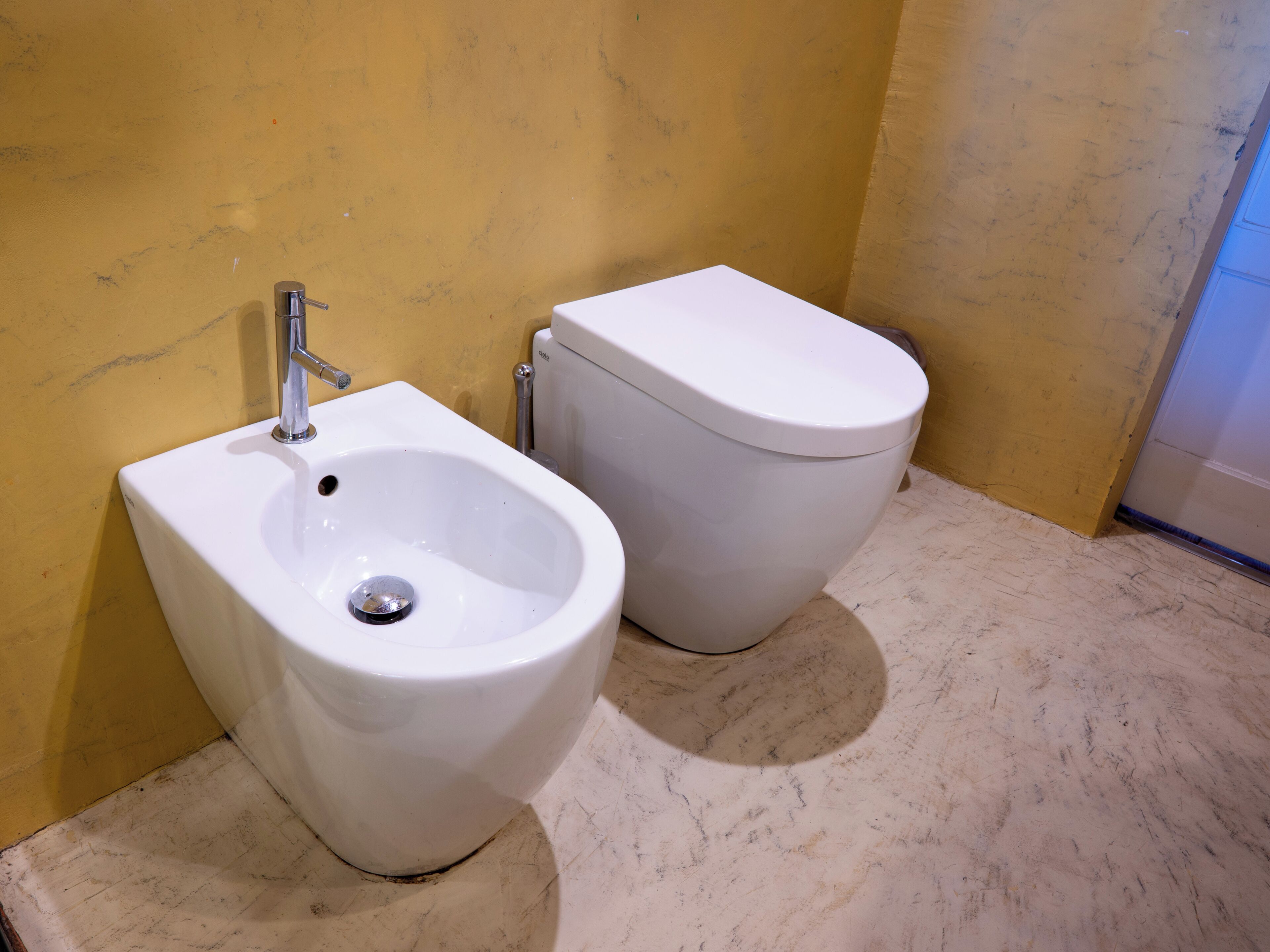 Un baño con bidé, inodoro y suelo de mármol.