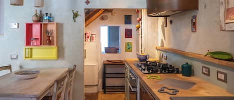 Una cocina compacta con estufa a gas, refrigerador y una mesa de comedor de madera con sillas.