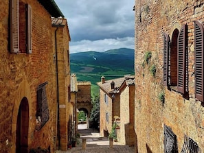 A narrow alleyway between buildings with arched doorways and a view of a valley. - Nido con vista (Radicondoli)