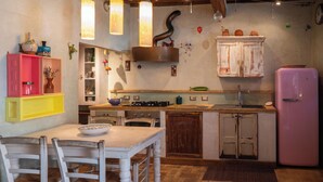 A kitchen with a dining table, chairs, a pink refrigerator, and wooden cabinets.