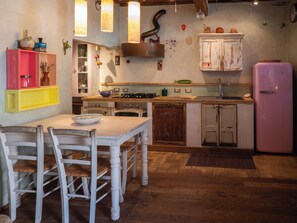 A kitchen with a dining table, chairs, a pink refrigerator, and wooden cabinets. - Nido con vista (Radicondoli)