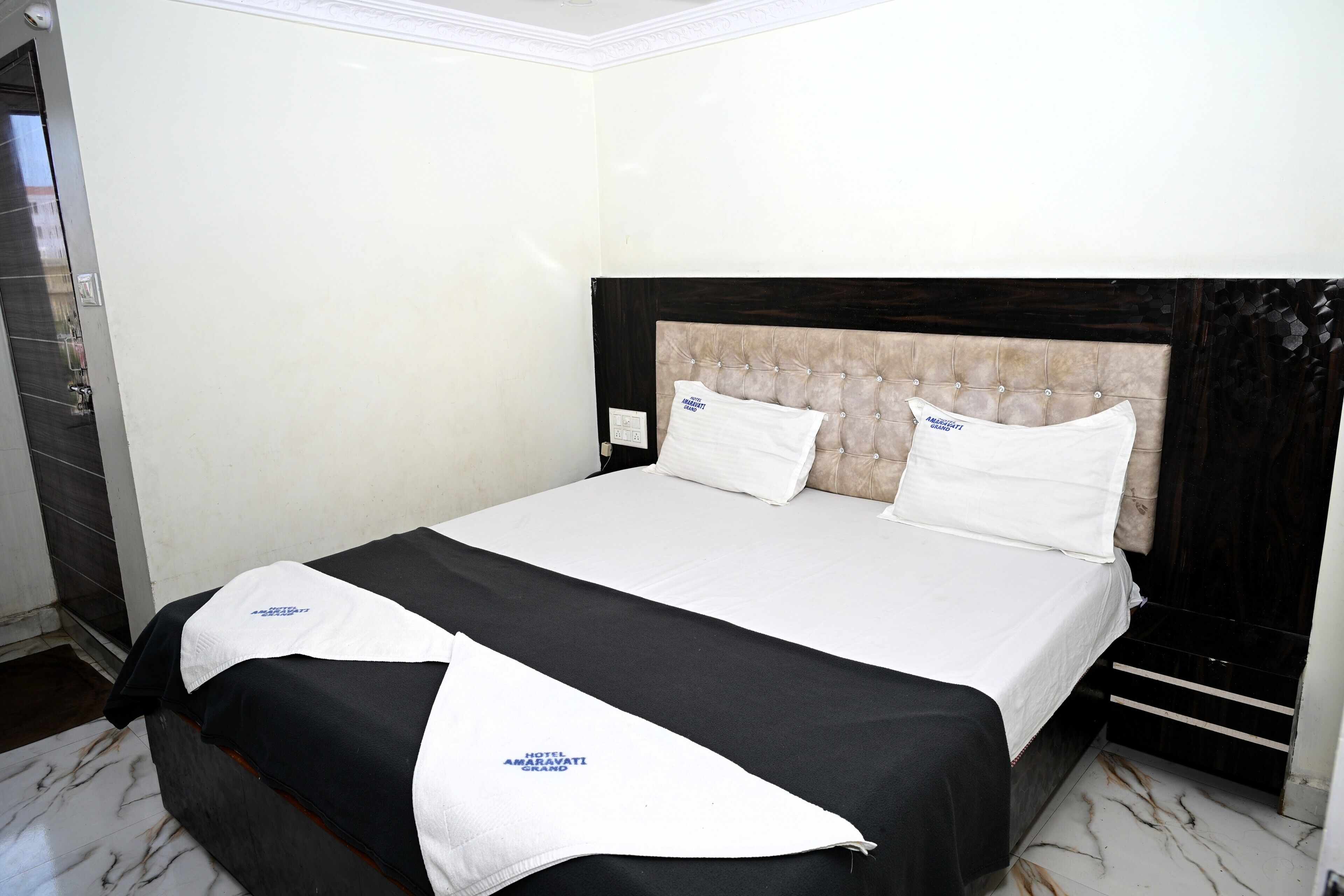 Habitación de hotel con cama, cabecera y lámpara de pared.
