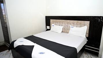 Habitación de hotel con cama, cabecera y lámpara de pared.