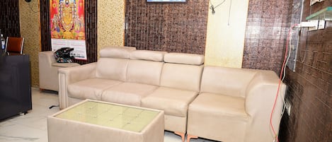 A beige sofa, a glass-top coffee table, and a wall with a Buddha image.