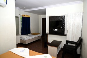 A small room with a bed, a desk, a chair, a TV, and a window with curtains.