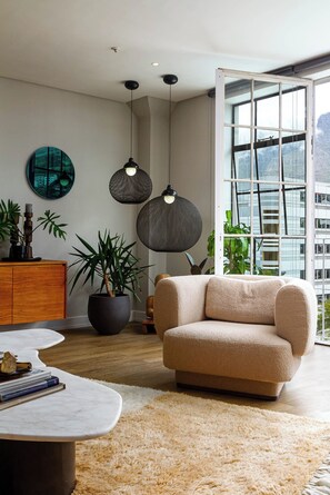 Un salon moderne avec un canapé, une table basse et une grande fenêtre donnant sur un immeuble.
