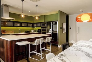 Une cuisine moderne dotée d’un îlot central, de tabourets de bar et d’une table à manger avec un plateau en marbre.