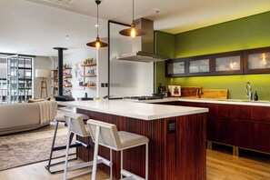 A modern kitchen with a central island, bar stools, and a green accent wall.