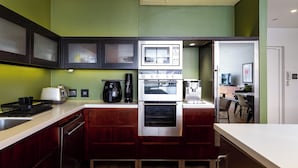 Uma cozinha compacta com micro-ondas, forno, máquina de café e uma pia pequena.