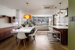 A modern kitchen with a marble countertop, wooden cabinets, and a dining area with a white table and chairs.