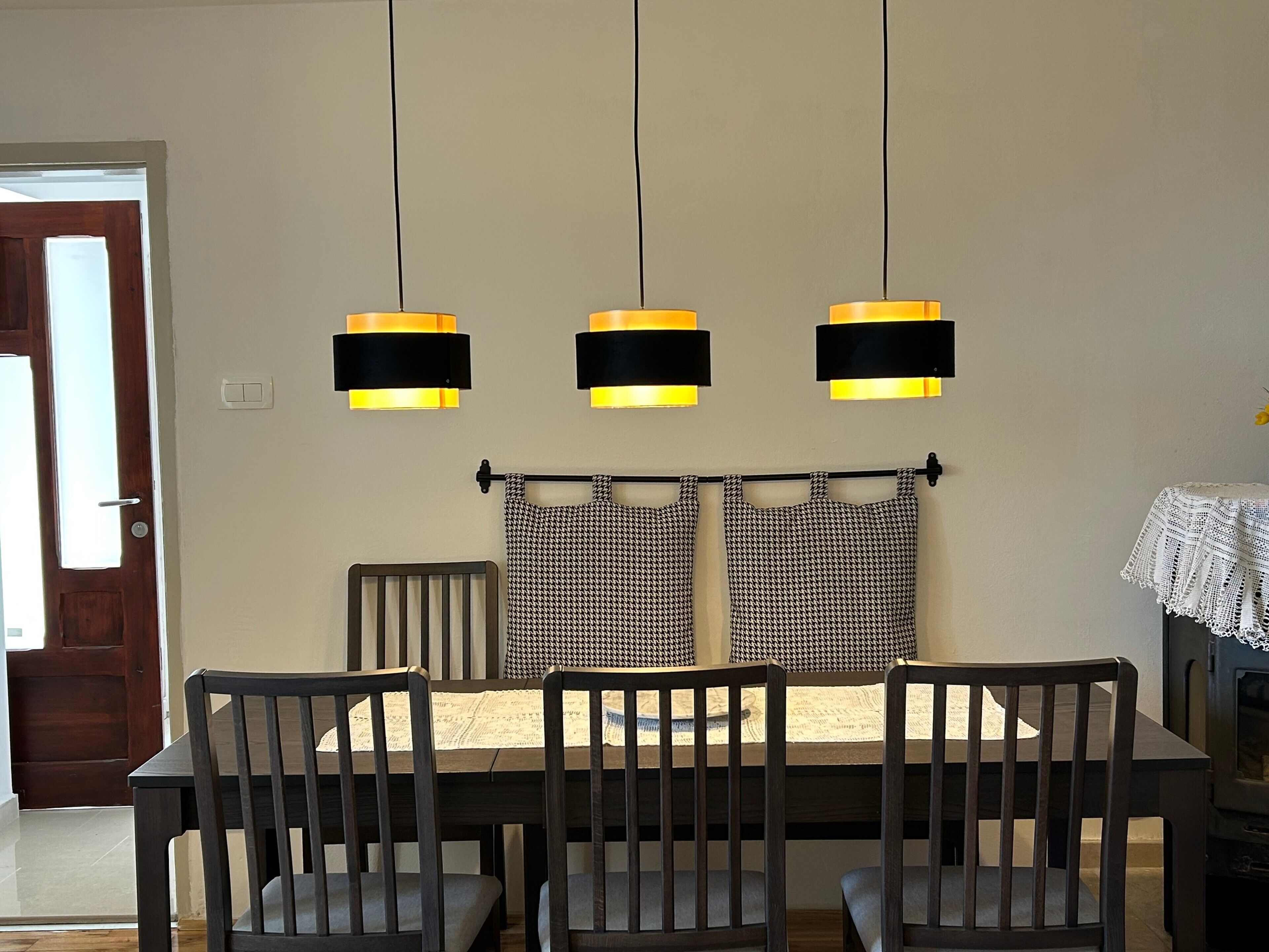 A dining area with a wooden table, four chairs, and three pendant lights.
