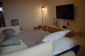 Une chambre d’hôtel avec un lit, une table de chevet, une lampe, une télévision et une chaise.
