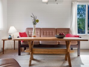 A room with a wooden table, a sofa, and a window with curtains. - "Hedwig" - 120m to the fjord by Interhome (Storvorde)