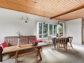 A modern living room with a wooden ceiling, a sofa, a dining table with chairs, and large windows. - "Hedwig" - 120m to the fjord by Interhome (Storvorde)