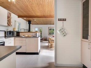 Eine moderne Küche mit Holzboden, weißen Schränken und einem Essbereich mit Tisch und Stühlen.