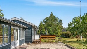 En bostadsfastighet med en asfalterad uppfart, en träbänk och en trädgårdsyta.