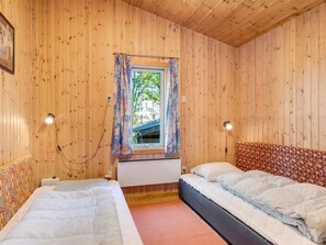 A room with wooden walls, a window with curtains, two beds, and bedside lamps. - "Hedwig" - 120m to the fjord by Interhome (Storvorde)