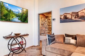 Sala de estar com sofá, mesa decorada e duas imagens penduradas na parede.