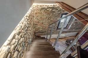 A wooden staircase with a stone wall on one side and a metal railing on the other. - Luxury Chianti Road - 3BR Free Parking (San Casciano in Val di Pesa)