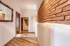 A hallway with a wooden floor, a brick wall, and a white radiator. - Luxury Chianti Road - 3BR Free Parking (San Casciano in Val di Pesa)