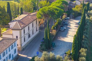 Une vue de rue avec des voitures garées, un bâtiment doté d’un toit en tuiles et une rangée d’arbres.
