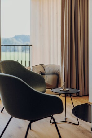 A modern living room with a sofa, armchair, and a small table. - Sona Suites Allgäu: Sauna, Hot Tub, and Mountain Views (Wiggensbach)