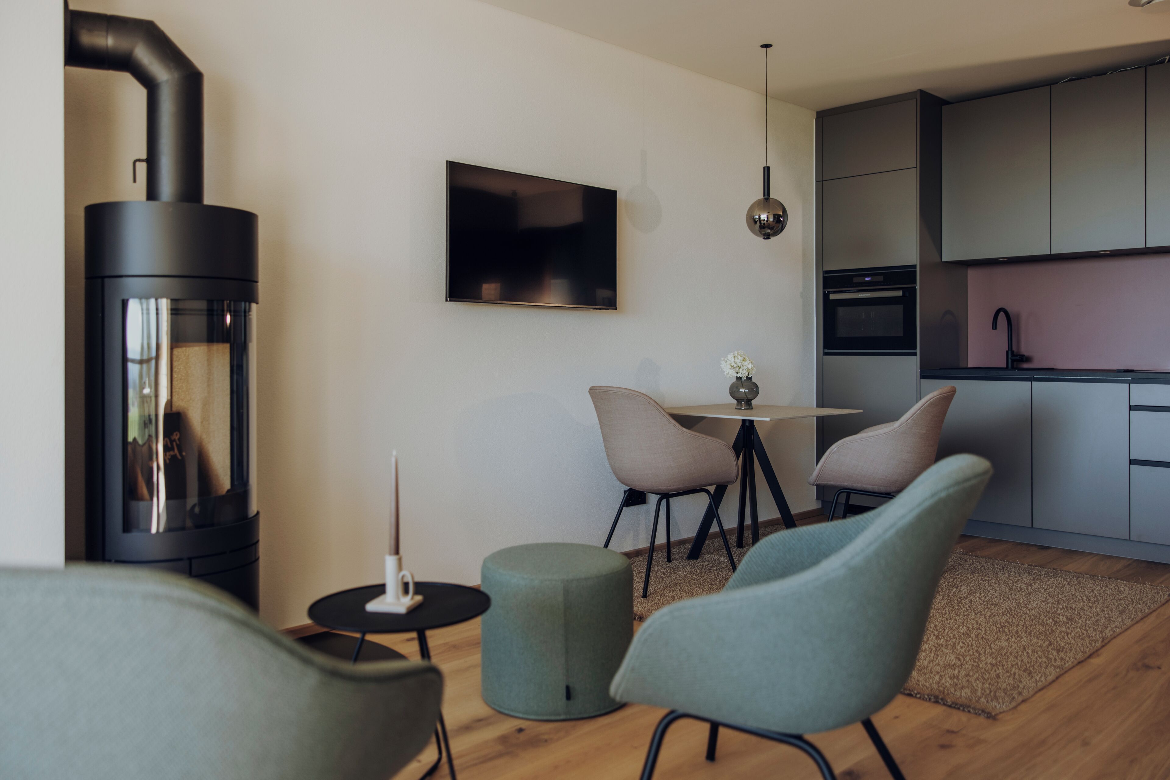 Una sala de estar moderna con chimenea, televisor de pantalla plana y comedor con sillas y mesa.