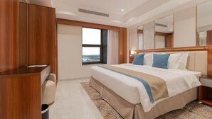 A hotel room with a large bed, a desk, and a window with a view. - Corp Yanbu Hotel B2 (Yanbu)